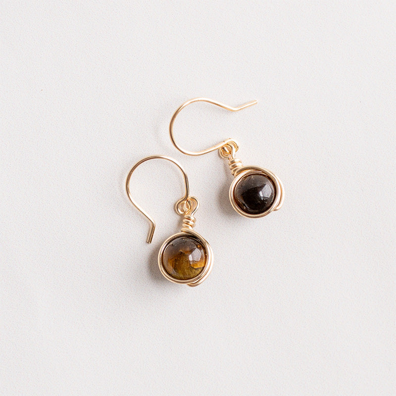 Aretes dorados con piedras marrones sobre fondo blanco