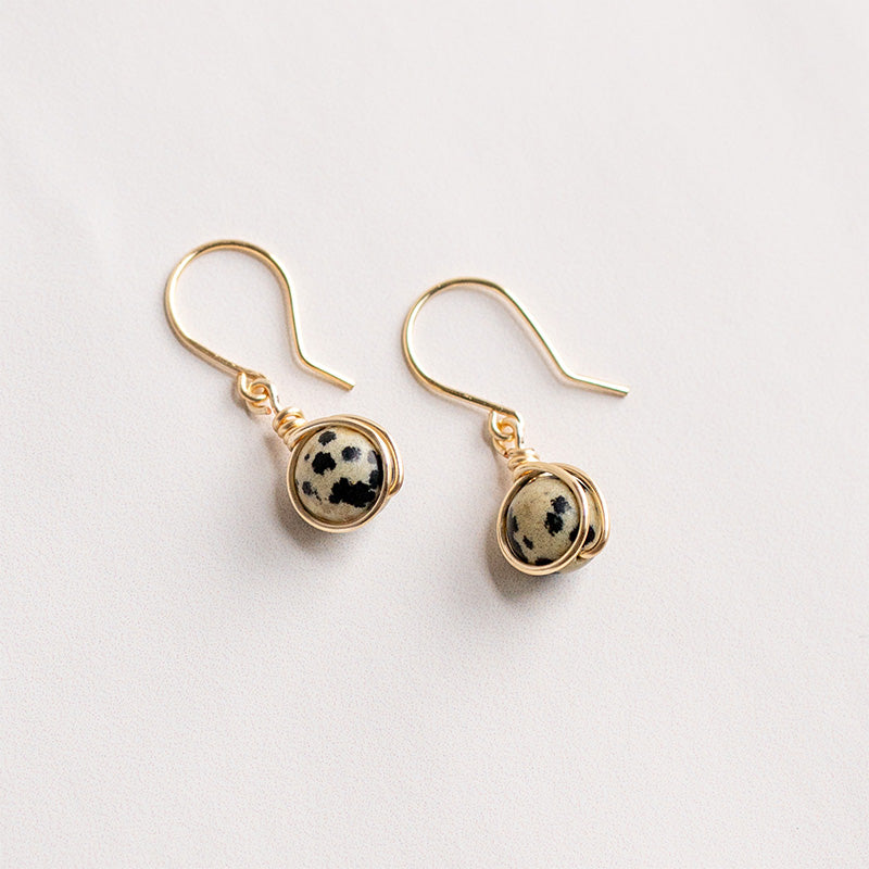 Aretes dorados con jaspe dálmata sobre fondo blanco