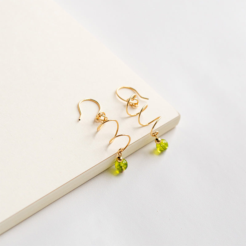 Aretes espiral con cuentas piedras naturales verdes sobre fondo blanco