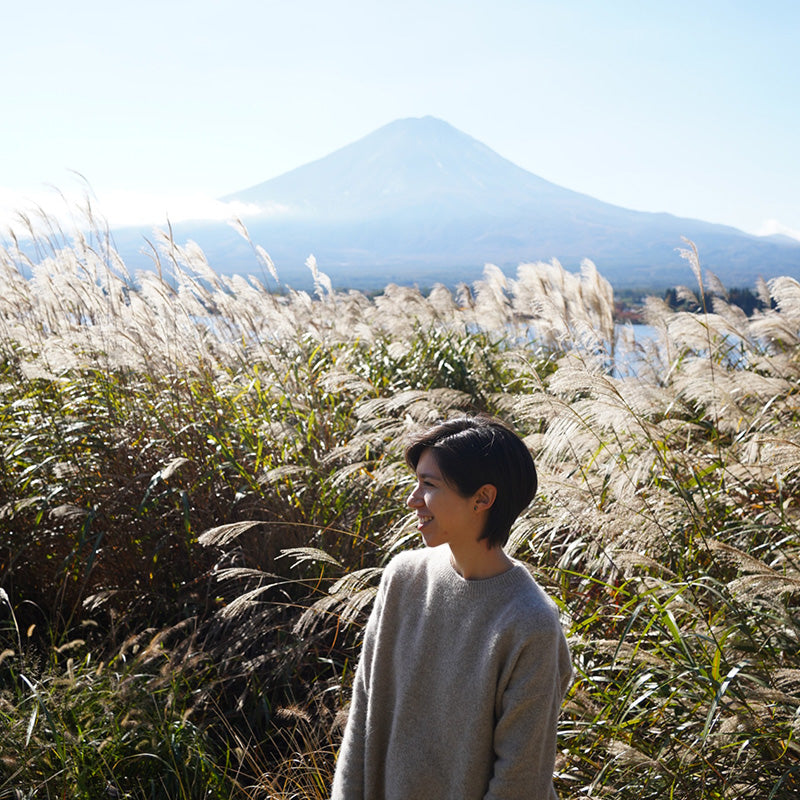 Persona de pie en un campo de hierba alta con el Monte Fuji al fondo